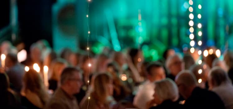 En grupp människor som sitter runt bord med levande ljus
