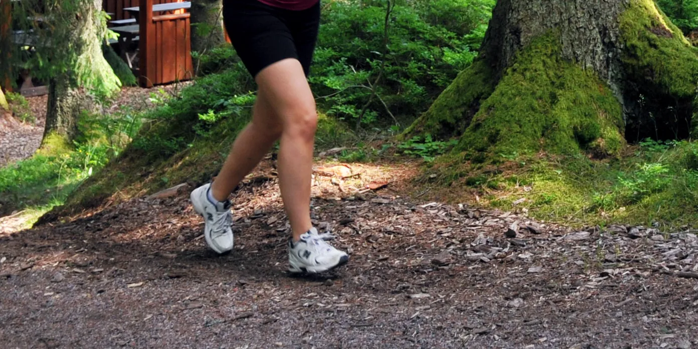 En kvinna som springer i skogen på en stig