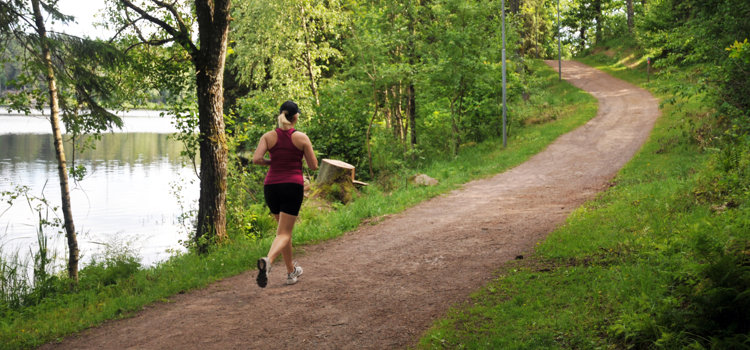 En tjej som springer på ett motionsspår i skogen.