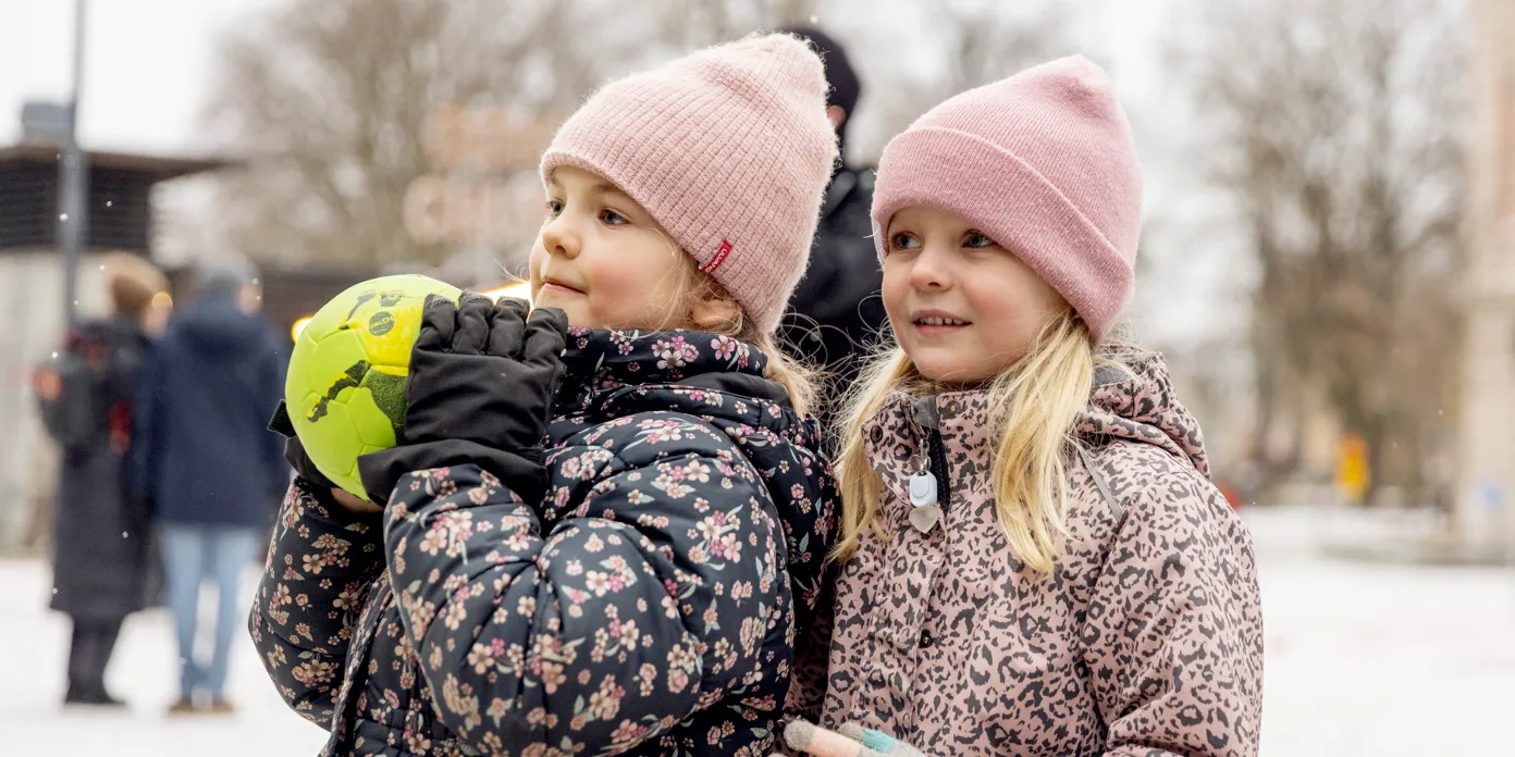 Två små flickor som står bredvid varandra i snön