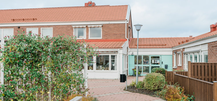 Ett hus med rött tegeltak intill ett staket