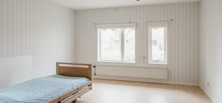 Ett tomt rum med en säng och ett fönster