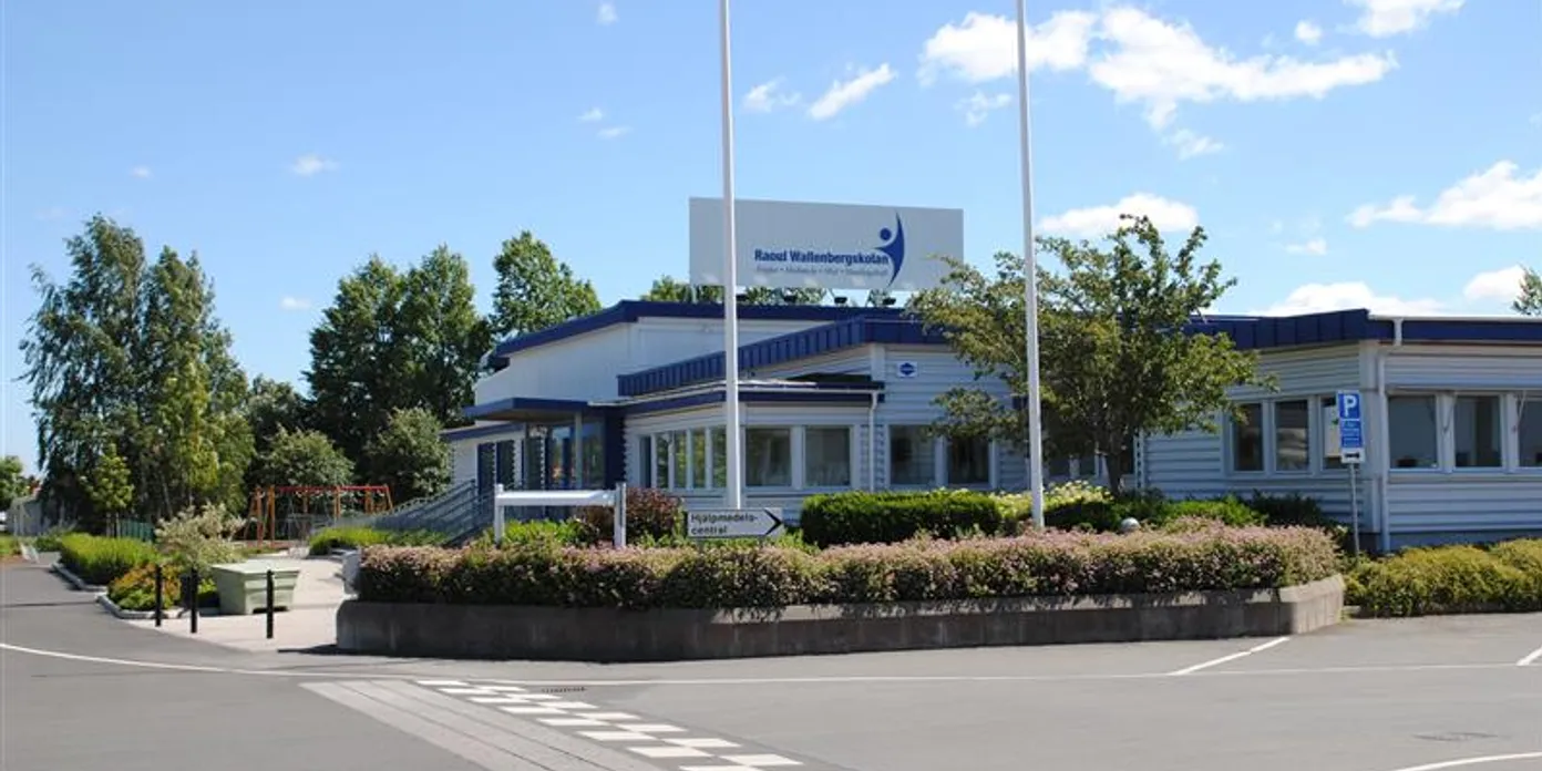 Vit skolbyggnad i en vägkorsning
