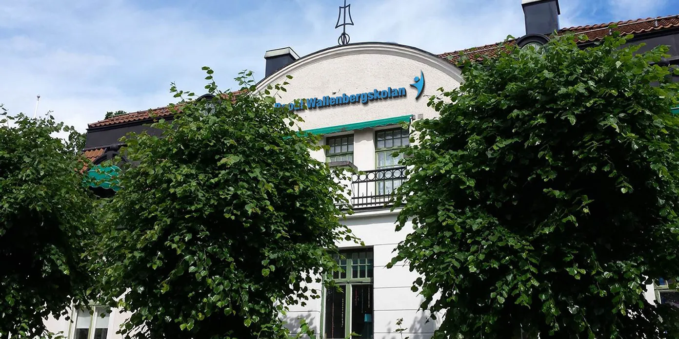 En stor vit byggnad med träd framför sig