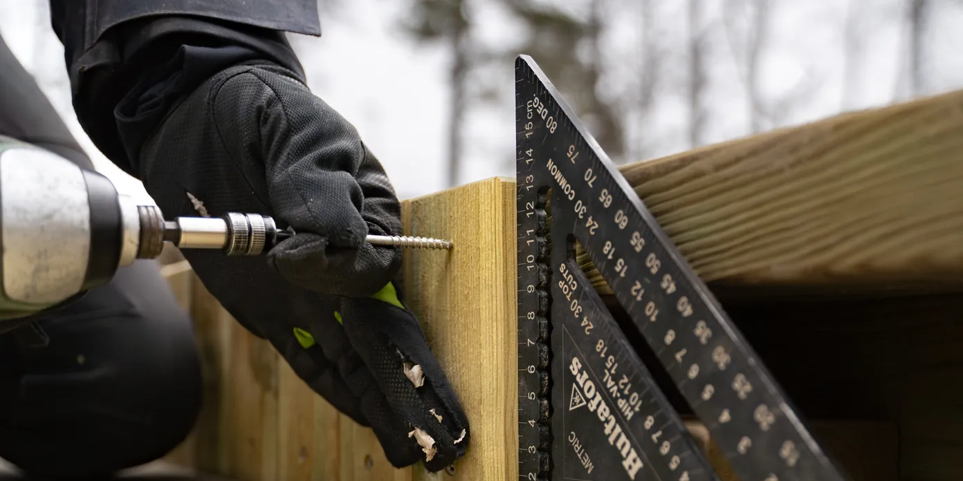 En person som använder en borrmaskin för att kapa en träbit