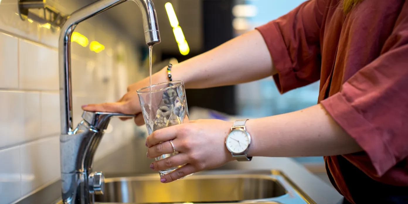 En kvinna fyller ett glas vatten från en kran