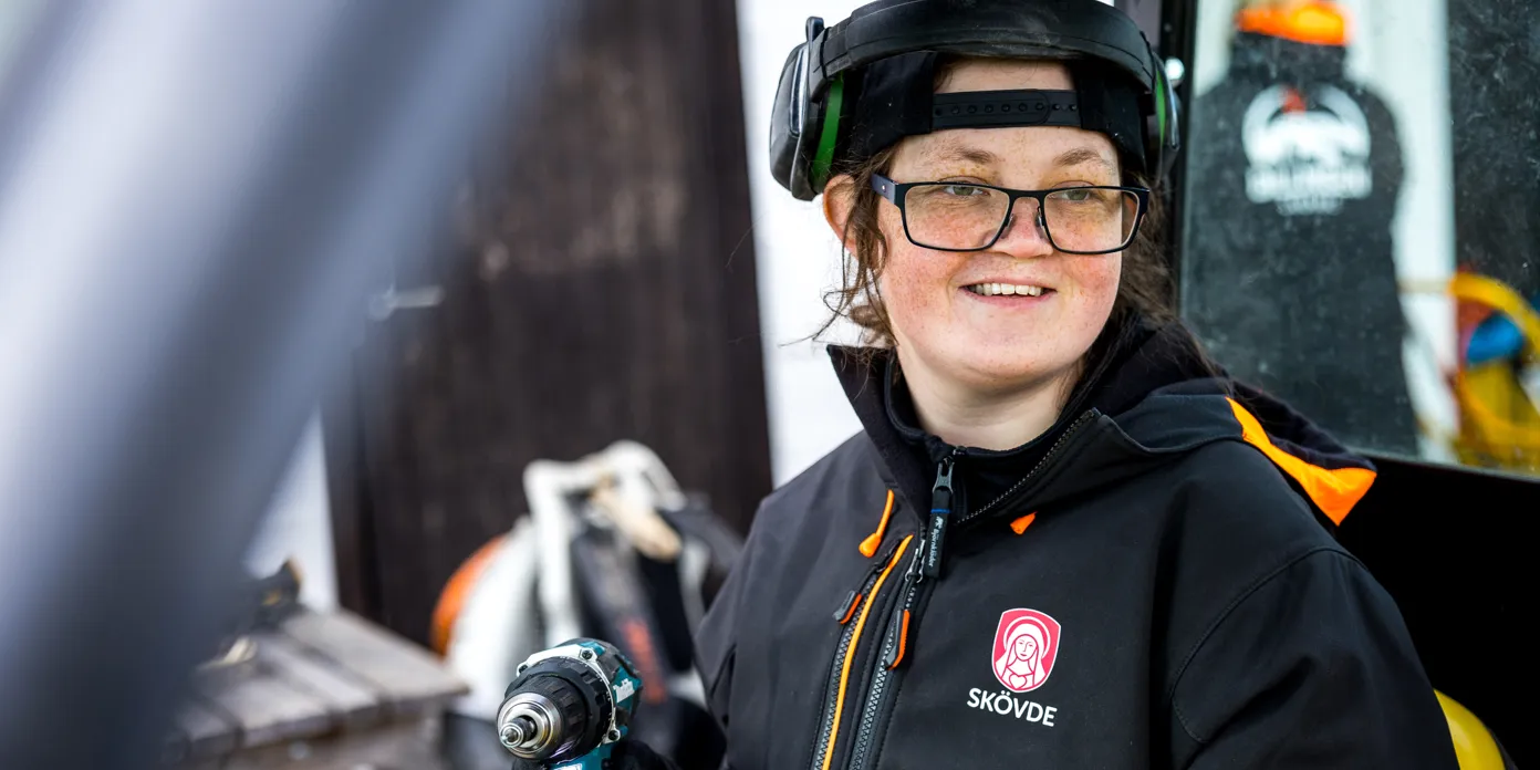En kvinna i svart jacka håller i en skruvdragare