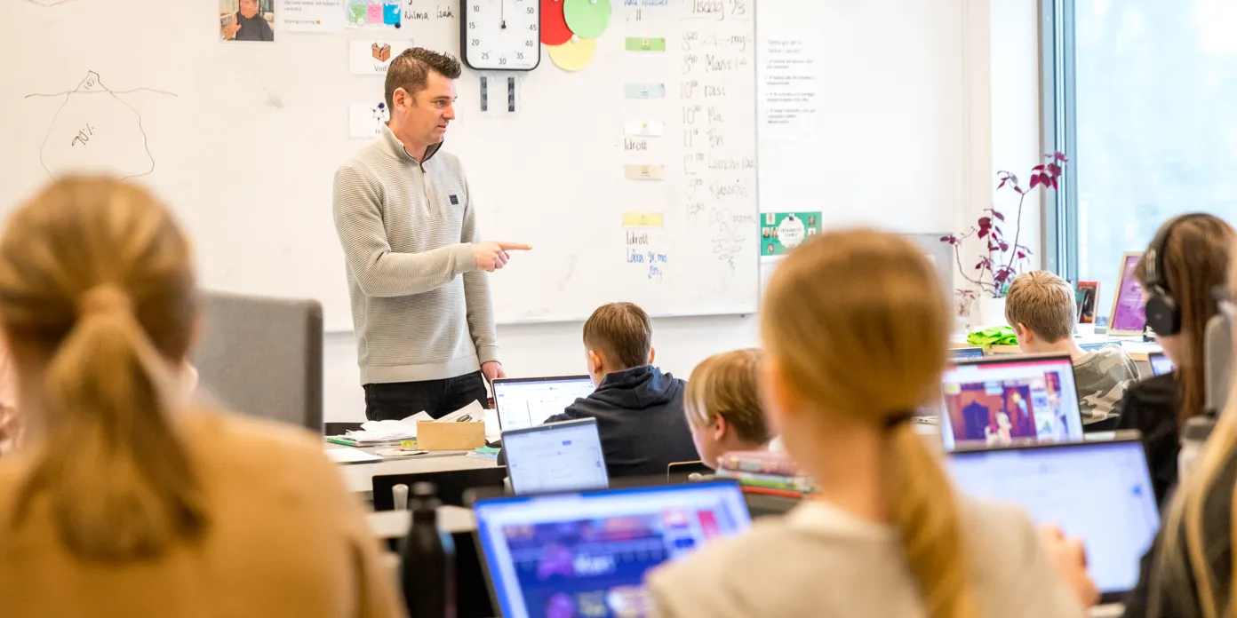 En man som står framför ett klassrum fullt av elever.